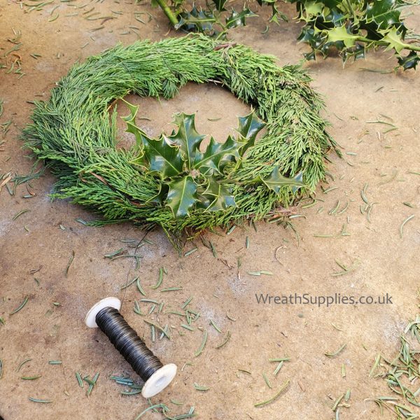 Binding holly to a conifer wreath base